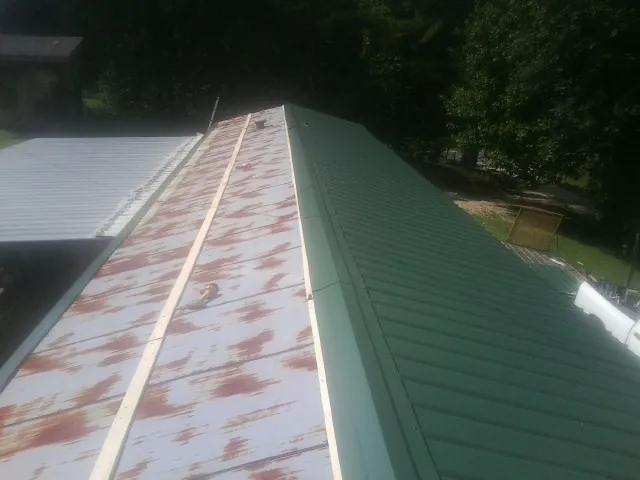Old rusted panels beside newly installed green metal roofing — Wind Damage Roof Repair by Roofing Brothers in New Liberty
