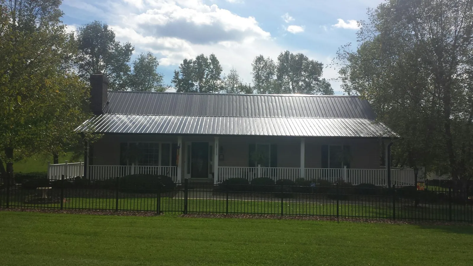 Gray metal roof on a brick ranch with a full width front porch — Gutter Guard Installation work by our crew in New Liberty