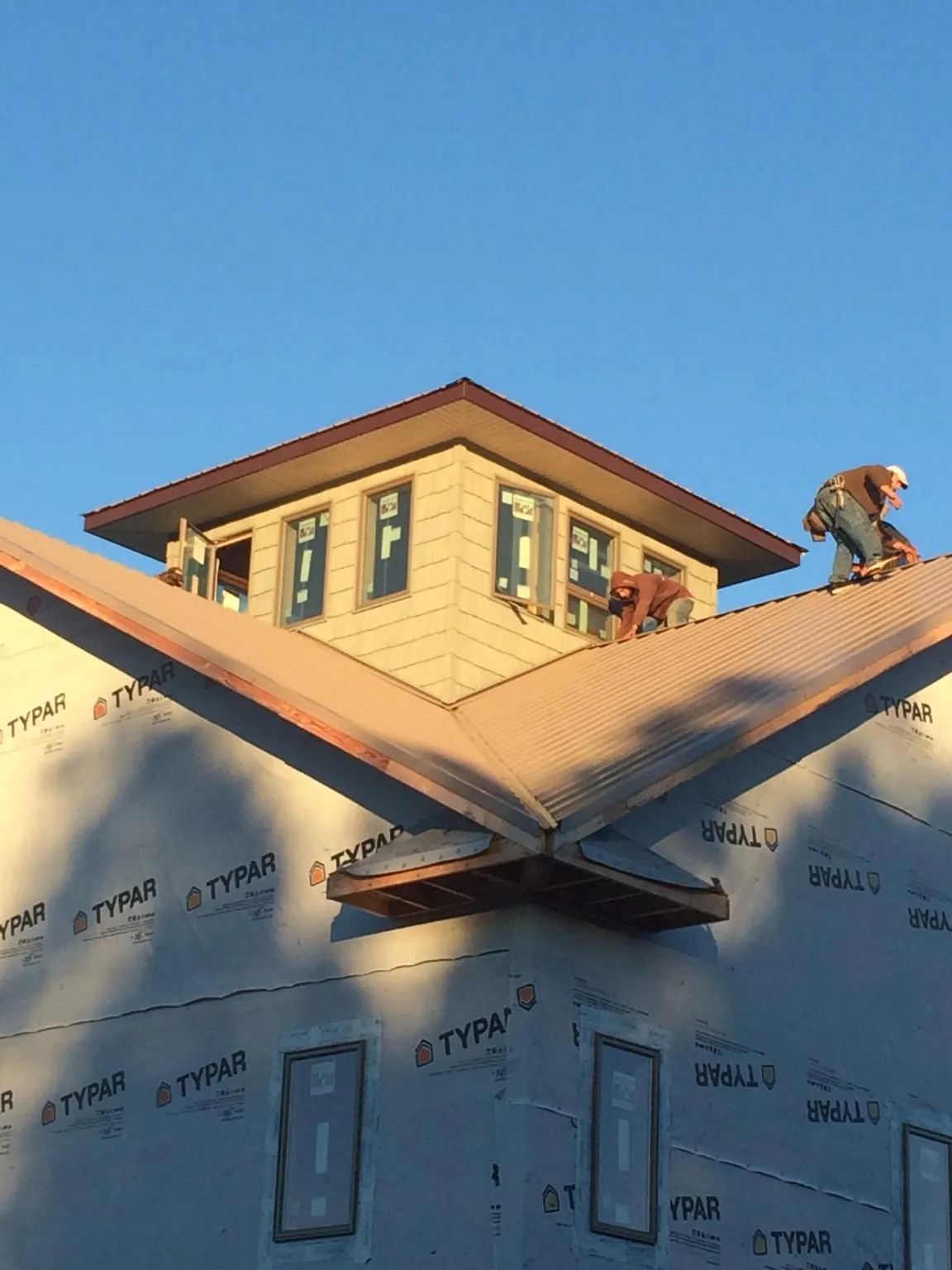 Roofers working around a rooftop cupola on a new metal roof at sunset — Roof Waterproofing in New Liberty by Roofing Brothers